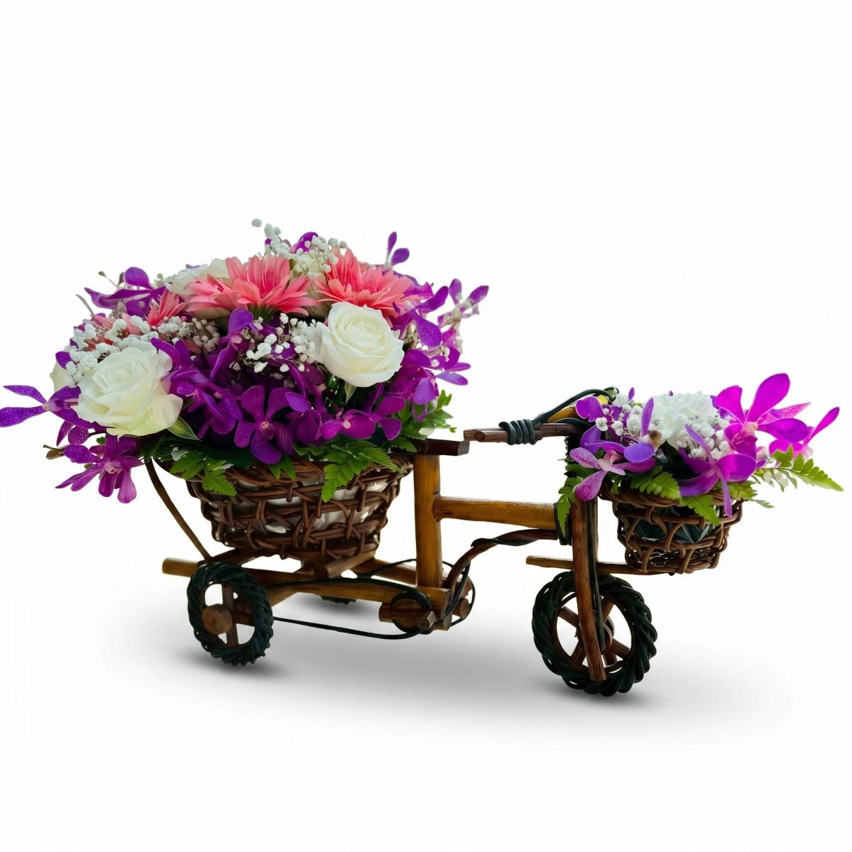 Flower bicycle basket arrangement with purple orchids, white roses, pink gerbera daisies, and white baby’s breath in a decorative mini bicycle basket. This floral basket has a soft pink, white, and purple color palette and is suitable for birthday flowers, congratulations flowers, thank you gifts, and decorative flower delivery in Chiang Mai.

Size : Length 60cm, Height 40cm