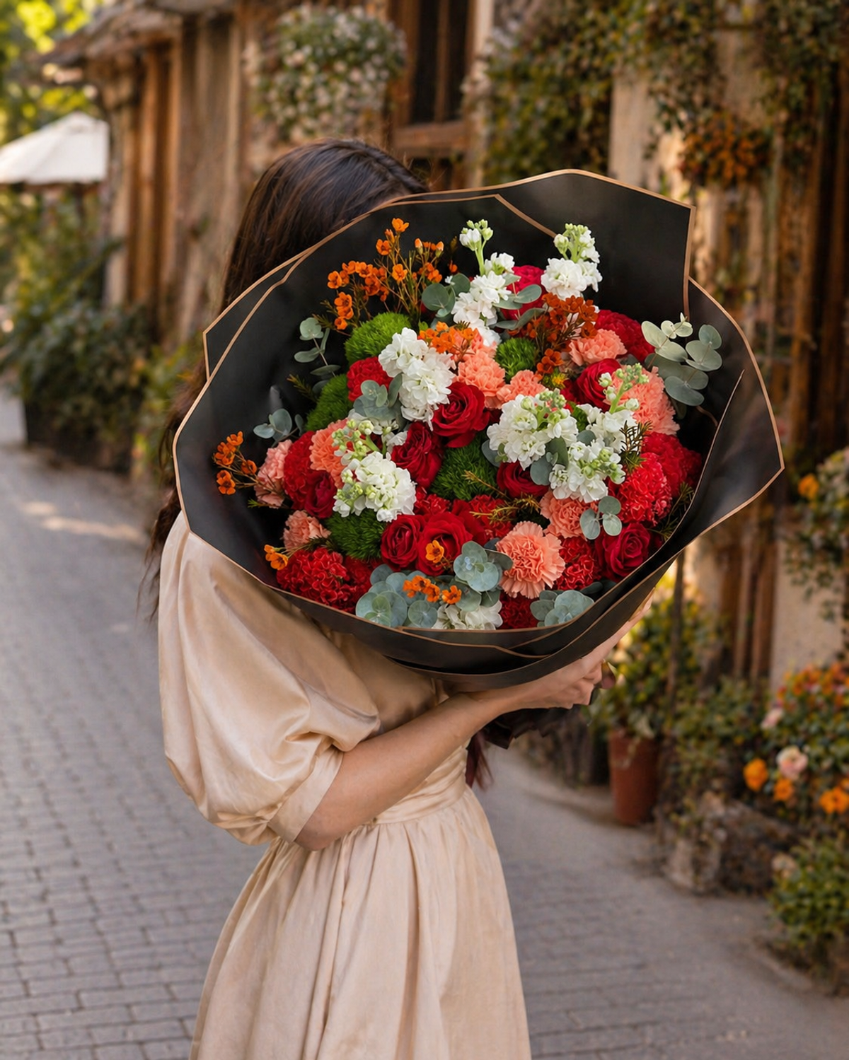 Premium flower bouquet with red roses, orange carnations, and white stocks in a luxury black wrap.
